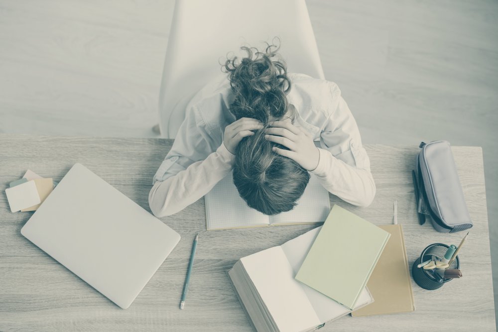 Niña con la cabeza apoyada sobre el cuaderno de estudio